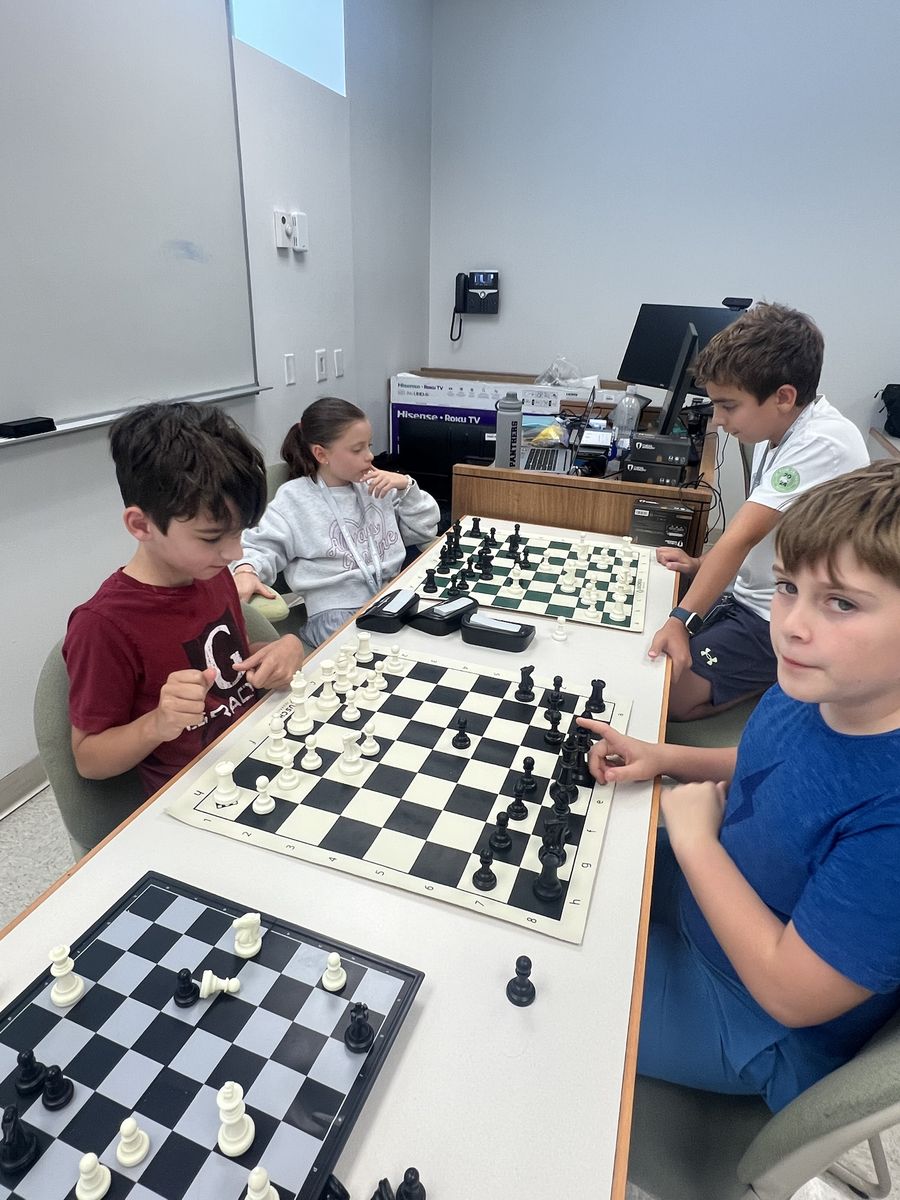 Students playing chess at a long table